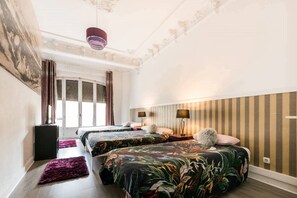 A hotel room with two beds, a large window, a ceiling fan, and a striped wall.