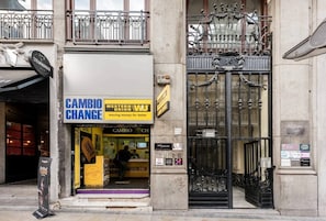 A building facade with a storefront labeled "CAMBIO CHANGE" and a black wrought iron gate with decorative elements.