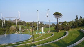A sports field with a large open area, surrounded by a curved pathway and trees.