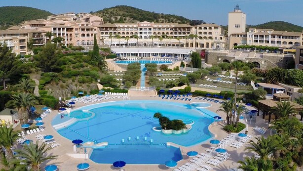 A resort with a large central pool, multiple smaller pools, and a variety of sun loungers and umbrellas.