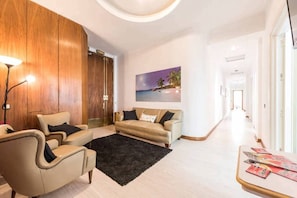 A modern living room with a beige sofa, a black rug, and a wooden wall.