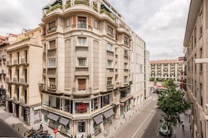 A multi-story hotel with a curved facade, balconies, and a visible storefront with a red sign.