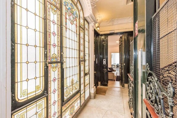 A corridor with ornate stained glass doors and a metal gate.
