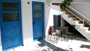 A blue door, a small table with chairs, and a staircase. - Agios Pavlos Hotel (Agios Vasileios)