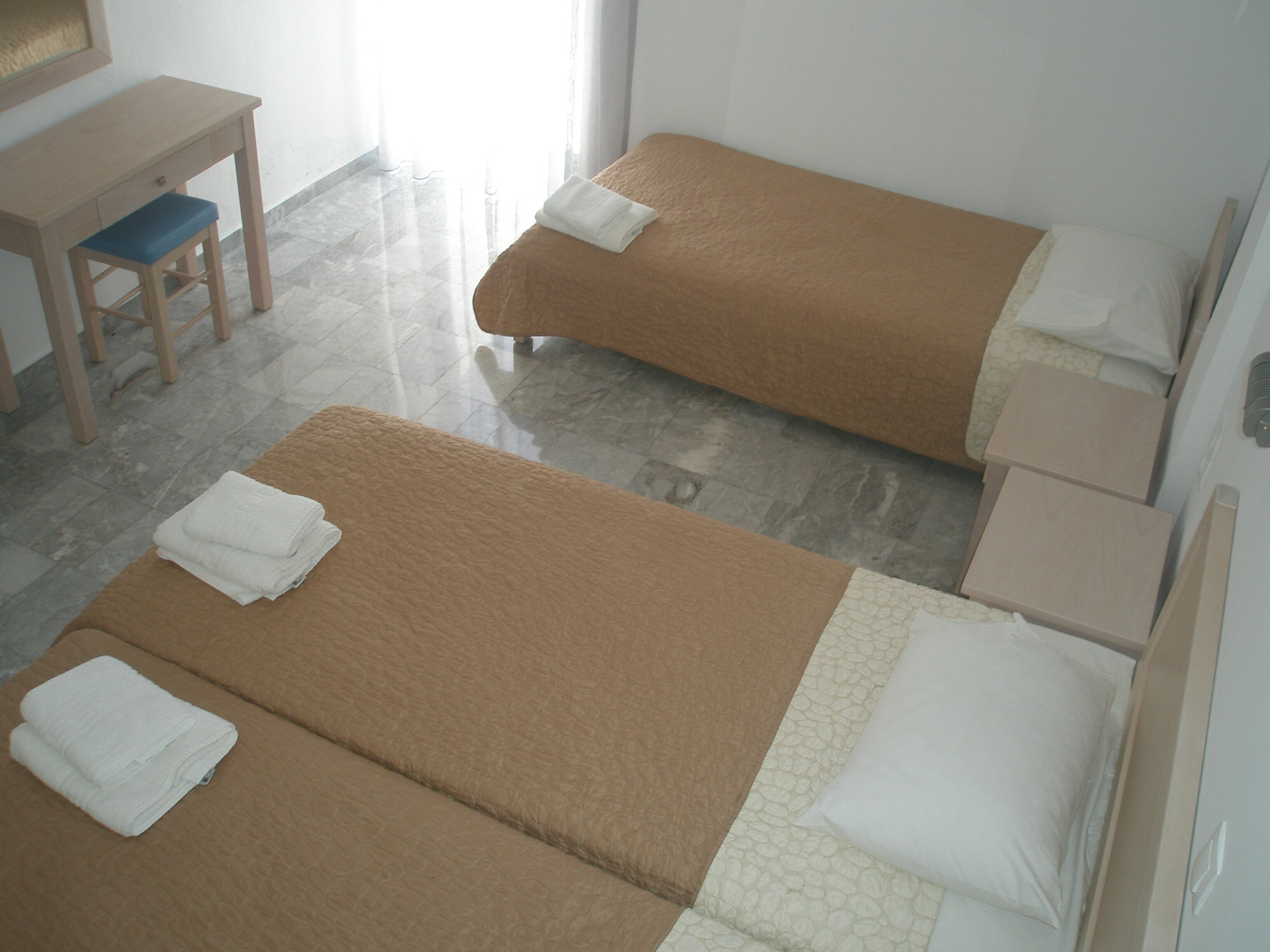Una habitación de hotel con dos camas individuales, un escritorio y una silla.