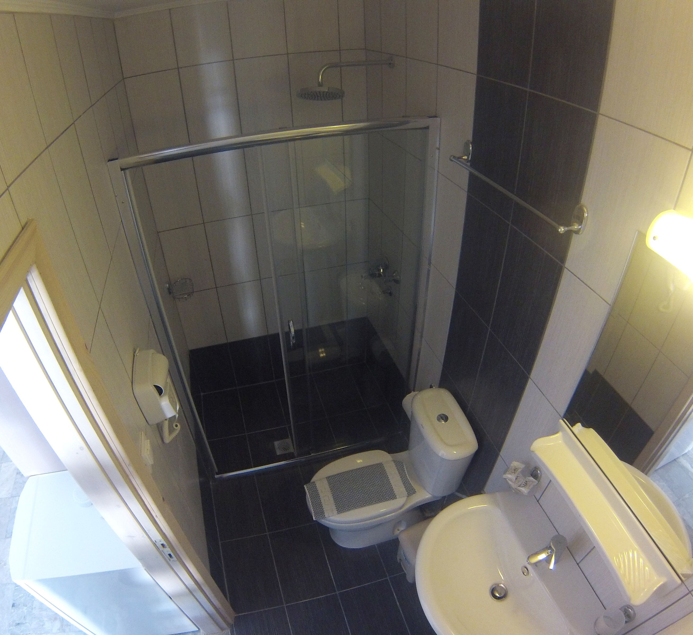 A compact bathroom with a glass-enclosed shower, a toilet, and a sink.