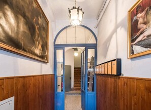 A hallway with wooden paneling, a blue archway, and a chandelier.