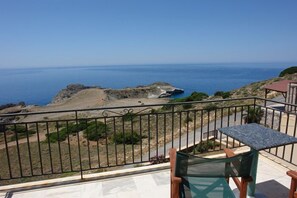 Un balcon avec vue sur la mer, une table et des chaises.