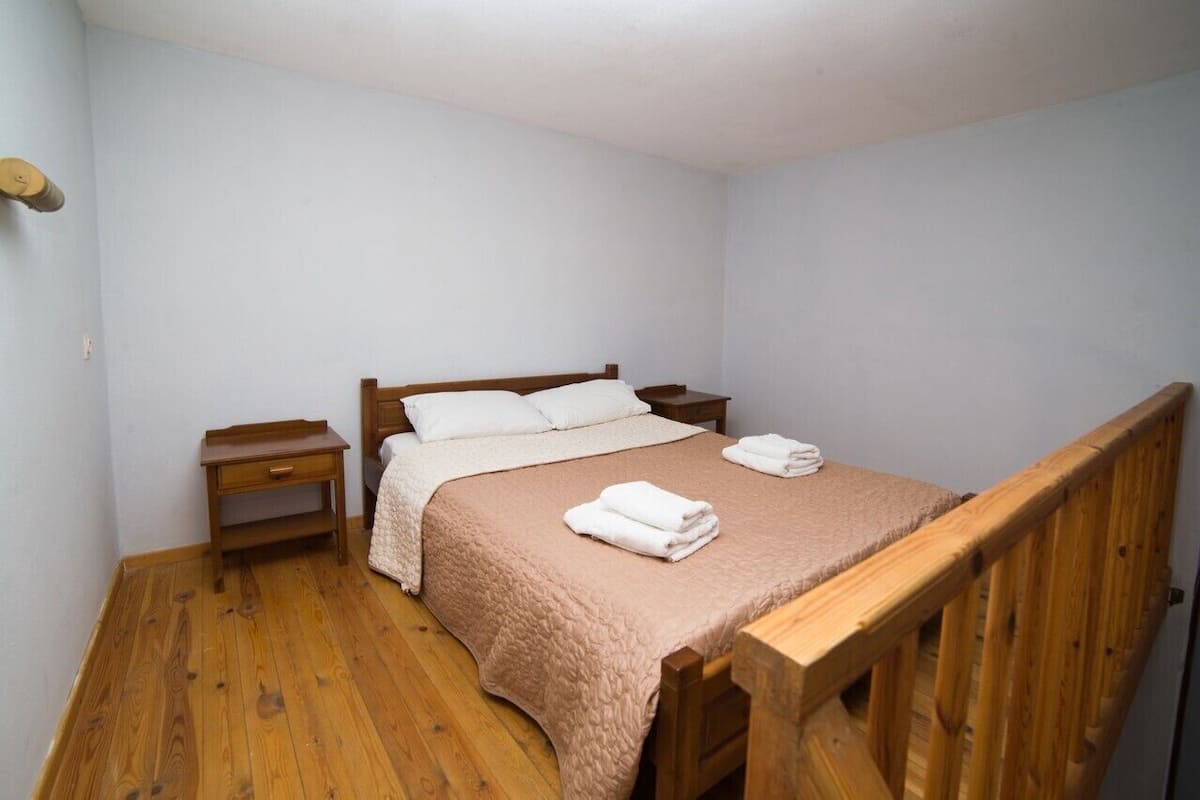 A single bed with a wooden headboard, a bedside table, and a nightstand.