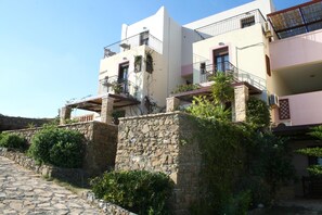 Un immeuble à plusieurs étages doté de balcons, de murs en pierre et d’un chemin pavé.