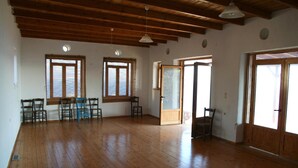 Una habitación amplia con suelos de madera, una mesa de comedor con sillas y ventanas grandes que dejan entrar luz natural.