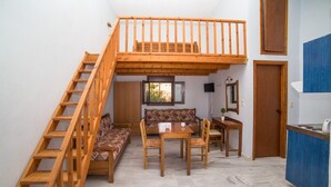 Un espacio habitable compacto con un entrepiso, comedor y kitchenette.