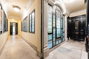 A hallway with ornate doors and large windows with decorative glass panes.