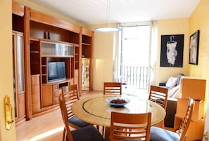 A dining area with a round table, chairs, and a television in a wooden cabinet.