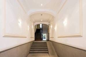 A wide, well-lit hallway with a staircase leading to an upper floor.
