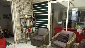 Una sala de estar con muebles de mimbre, una estantería y un sofá rojo.