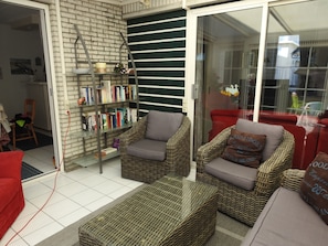 A living room with wicker furniture, a bookshelf, and a red sofa.