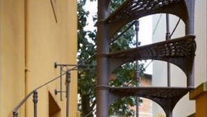 A narrow outdoor staircase with wrought iron railings and a metal handrail, leading to a gated entrance. - A Romantic Retreat in Florence.  (Firenze)