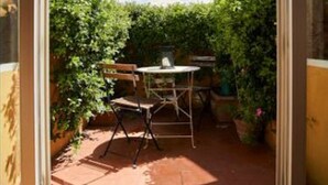 A patio with a table and chairs, surrounded by dense foliage and a clear sky. - A Romantic Retreat in Florence.  (Firenze)