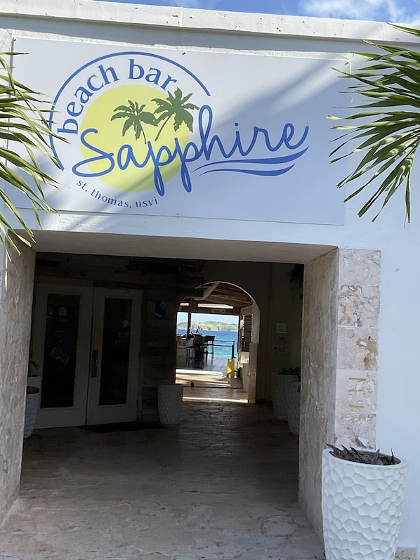 A beach bar named 'Sapphire' with a view of the sea in the background.