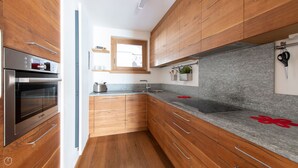 Una cocina moderna con armarios de madera, horno Bosch, encimeras de granito y una ventana sobre el fregadero.