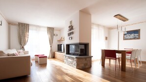 Una sala de estar con chimenea, un sofá, un televisor y un comedor con sillas.