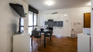 A compact kitchen with white cabinets, a black countertop, and a dining area with a table and chairs.