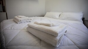 A neatly made bed with folded white towels and pillows.
