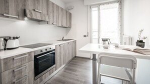 Eine moderne Küche mit Holzschränken, einer weißen Arbeitsplatte und einem Essbereich mit Stuhl und Tisch.