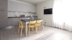 A modern kitchen with grey cabinets, a microwave, and a dining area with yellow chairs. - Italianway - Giuseppe Pastine 17/D (Santa Margherita Ligure)