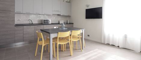 Una cocina moderna con armarios grises, un microondas y un comedor con sillas amarillas.