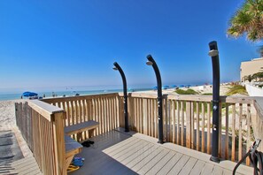 A wooden deck with benches and a railing overlooking a beach.