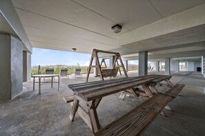 Een overdekt buitengebied met picknicktafels en stoelen.