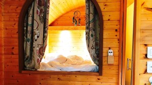 Acogedora habitación de cabaña con interior de madera, un banco, una mesa y una ventana con cortinas.