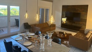 Un coin repas avec une table dressée pour deux personnes, un canapé et un téléviseur en arrière-plan.
