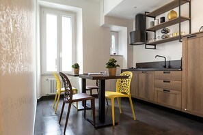 A modern kitchen with a dining table, chairs, and a built-in shelf with kitchenware. - My Love Suite (Rome)