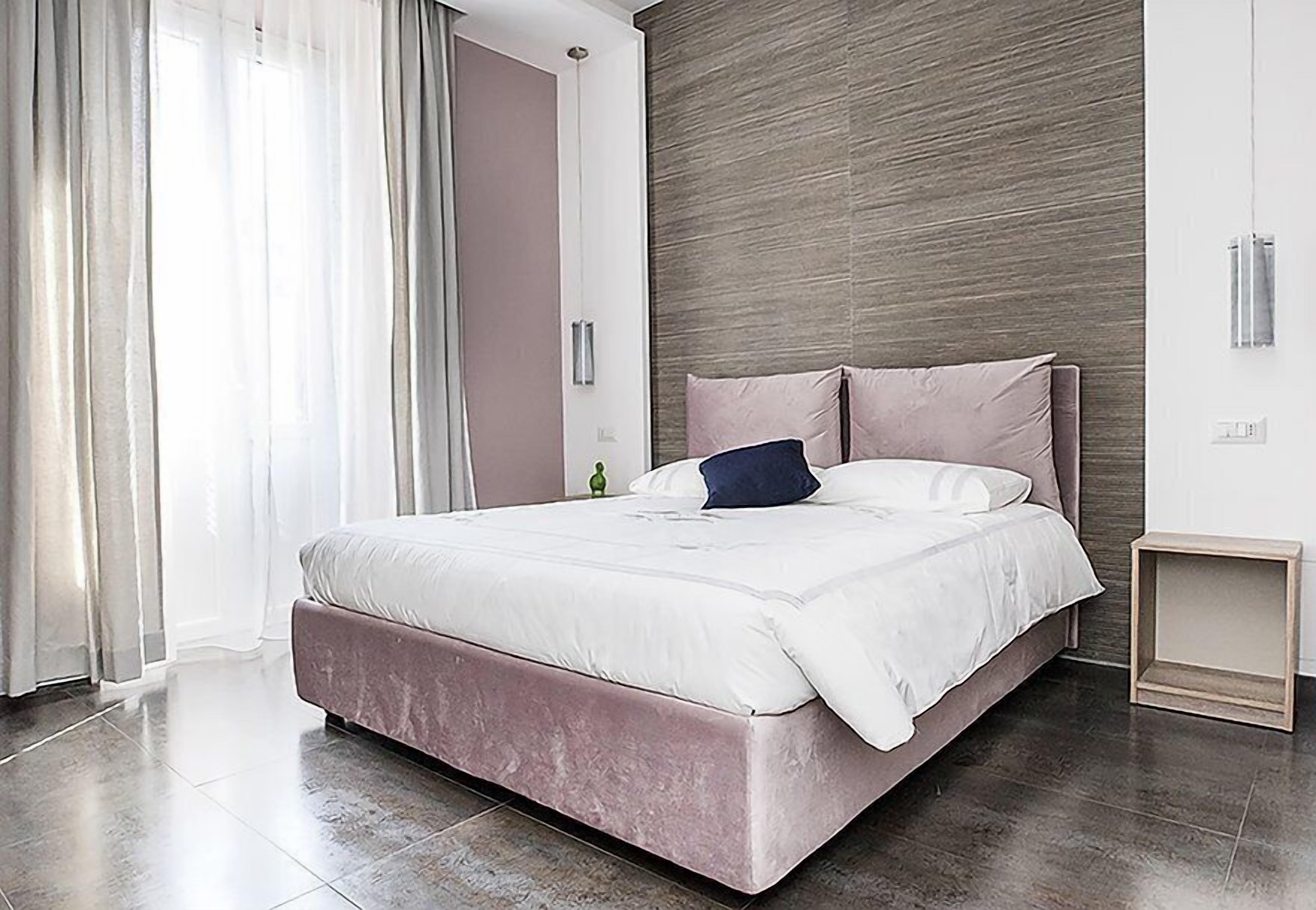 Un dormitorio moderno con una cama grande, un cabecero de madera y una mesita de noche pequeña.