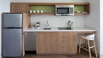Une cuisine compacte équipée d’un réfrigérateur, d’un four à micro-ondes, d’un évier et de meubles de rangement en bois.