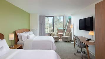 A hotel room with two beds, a desk, a chair, and a TV.
