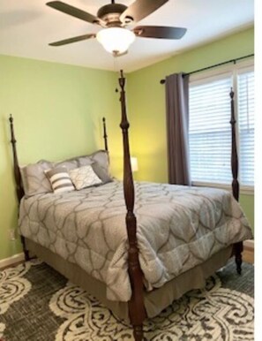 Uma cama com dossel e colcha acolchoada em quarto com paredes verdes e carpete estampado.