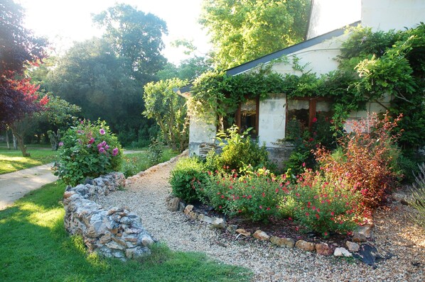 A stone pathway leading to a house with a garden.