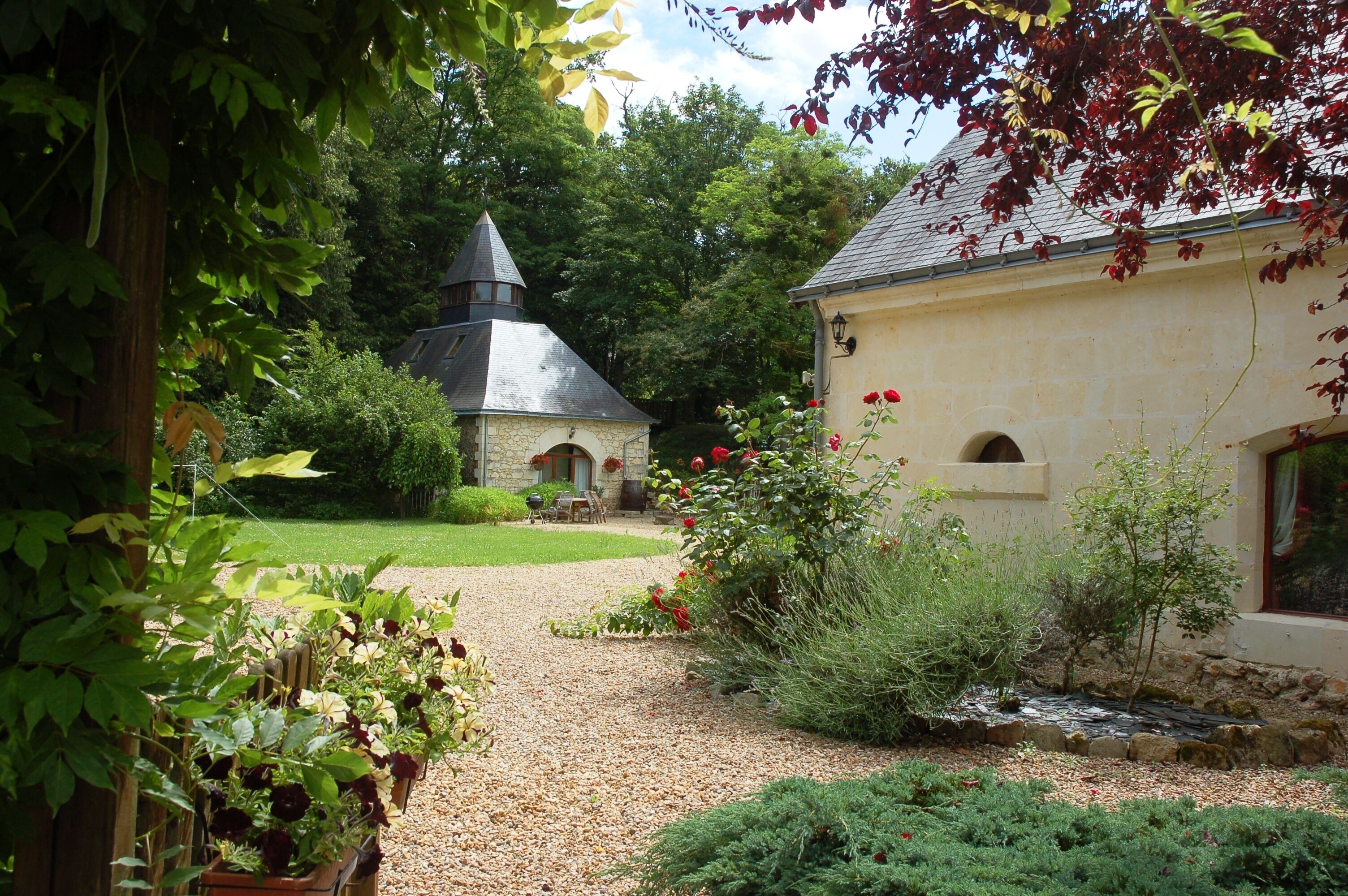 A garden with a stone building, a small pond, and various plants.