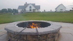 A stone fire pit with a metal grate in the center, surrounded by a stone border.