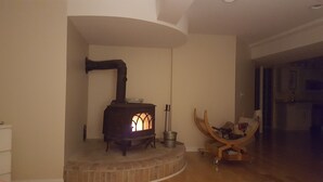 A room with a wood-burning stove, a wooden chair, and a small table.