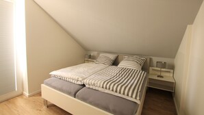A bedroom with a bed, bedside tables, and a window.