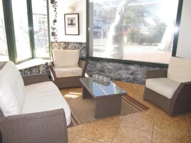 Une pièce meublée de meubles en osier, avec une table basse et une vue sur l’extérieur.