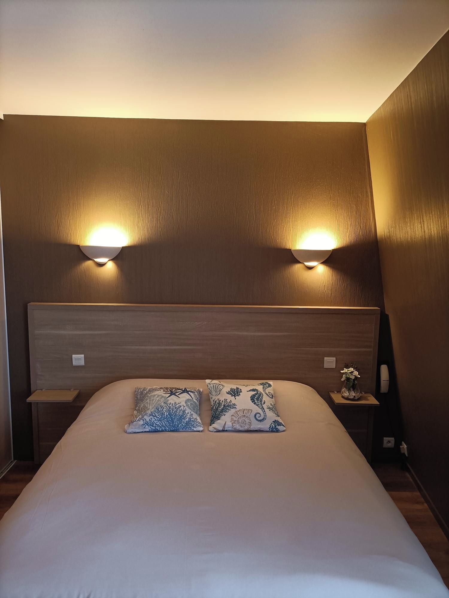 Une chambre à coucher avec une tête de lit en bois, deux lampes de chevet et deux coussins décoratifs.