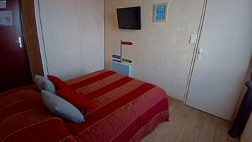 A bedroom with a bed, a TV mounted on the wall, a sign indicating a fishing trip, and a wardrobe.