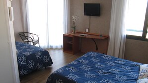 Habitación de hotel con dos camas, un escritorio, una silla y un televisor.