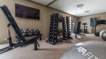 A gym with exercise equipment, a TV, and a mirror.
